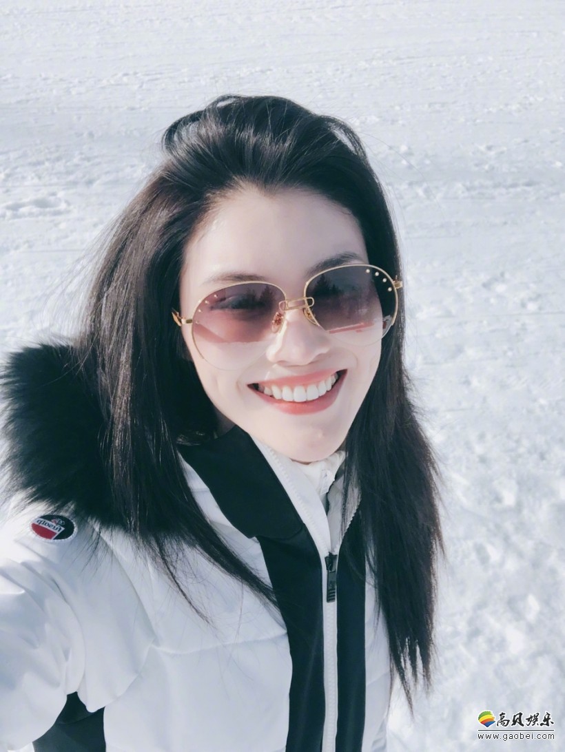 何穗晒出滑雪照片:穿着白色滑雪服坐在雪地上,一双长腿占满屏幕