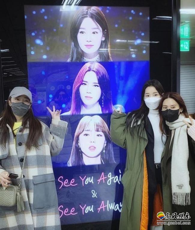 韩国女团See Ya三名成员一同在See Ya14周年演唱会宣传海报前拍摄照片