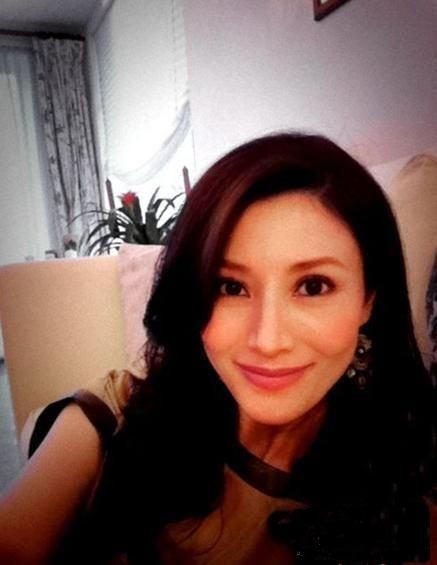 李嘉欣素颜与马合照：摸着吃着饲料棕色马匹的头，笑容灿烂似少女