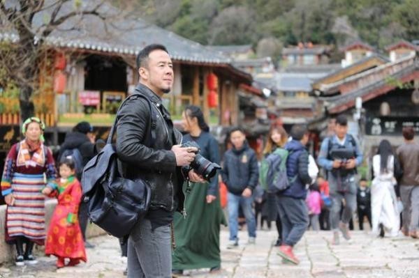 杨坤古镇街头背着包，手握单反，走走停停，边走边拍，颇具文艺范