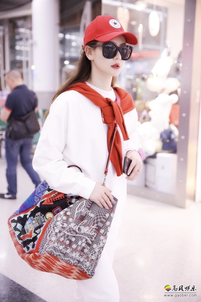 戚薇现身北京机场，戴红色鸭舌帽，穿红色鞋子，红色卫衣披在肩头