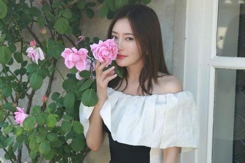 秦岚微博晒出美图：穿着黑白搭配的衣服，小露香肩，置身花畔轻嗅芬芳