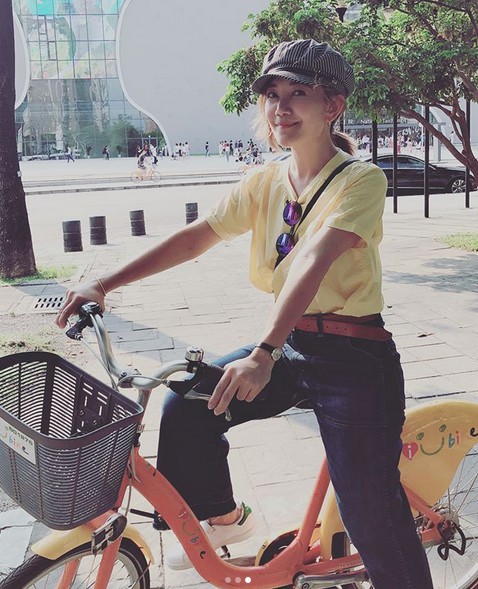 梁静茹晒出一组照片：身穿亮黄色T恤骑车，笑容明媚动人，少女感十足