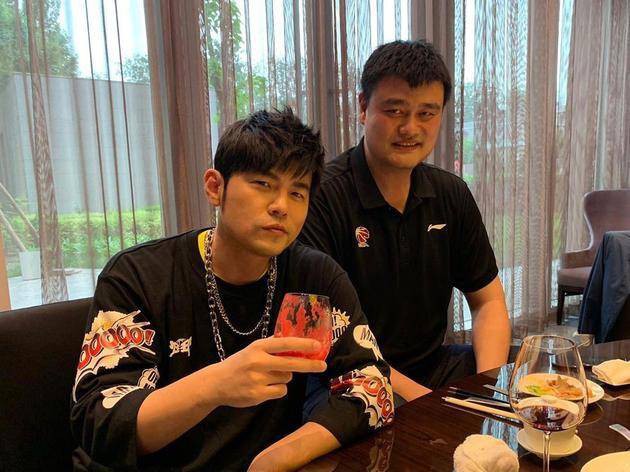 周杰伦晒出与姚明合影：周杰伦与姚明在餐桌前举杯合照，两人面带微笑