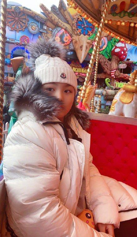 王诗龄晒出游乐场玩耍照，身穿黑色裤子搭配白色羽绒服，戴着白色绒线帽