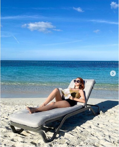 郑秀妍晒出自己在海边晒着日光浴美照！她戴着墨镜躺在沙发椅上手拿新书