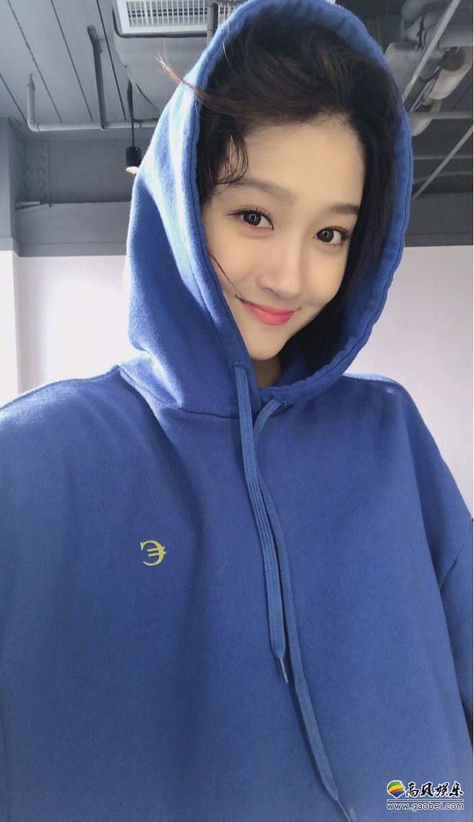 关晓彤微博晒出美照，她身穿蓝色连帽卫衣，摆出各种pose，露出甜美笑容